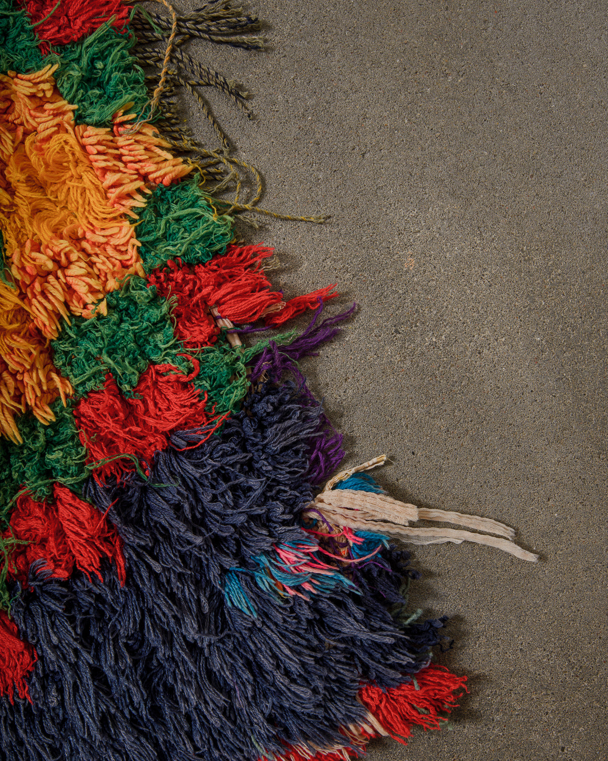 close up of end of boucherouite rug with many colours and roughly finished edge.